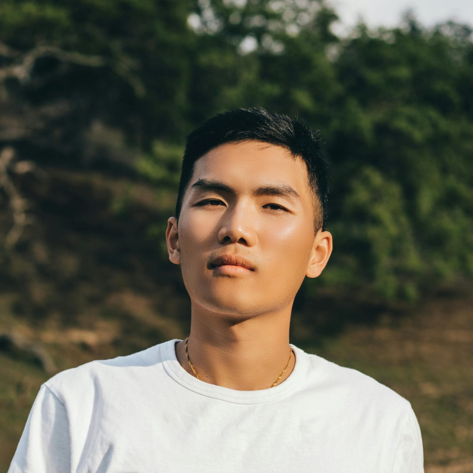 Young man posing outdoors in casual fashion with a relaxed expression.